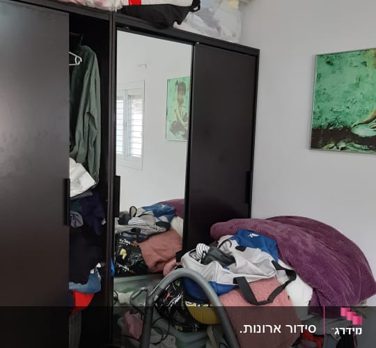 ארון בגדים עם בגדים מקופלים ושואב אבק על הרצפה